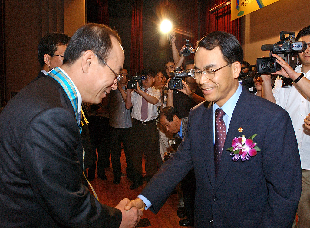 Min Rae Cho, executive vice-president and head of SK Telecom`s Community Relation Group, is shown receiving the `Silver Tower Award` for Industrial Service Merit from Daeje Chin, Minister of Information and Communication, at a ceremony commemorating the 17th National Information Culture Month 